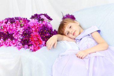 Kız bir buket çiçek yanında oturuyor.