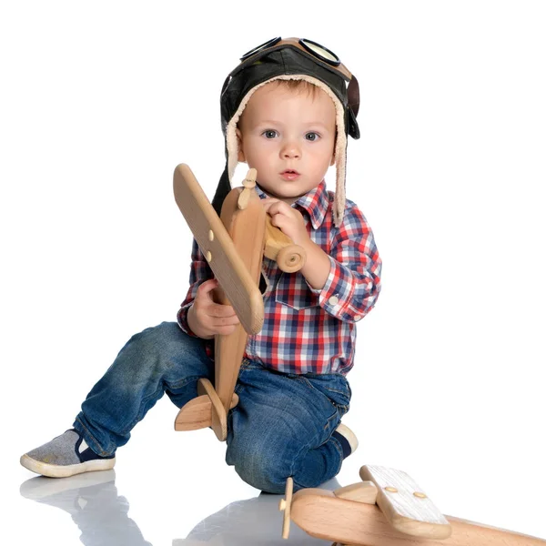 Un ragazzino con un berretto da pilota e un aereo di legno in mano — Foto Stock