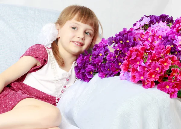 Fille s'assoit à côté d'un bouquet de fleurs . — Photo