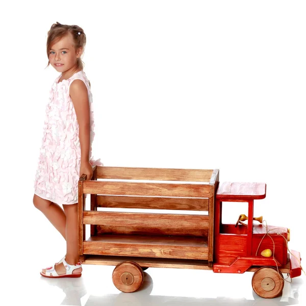 Κοριτσάκι παίζει με ένα ξύλινο αυτοκίνητο. — Φωτογραφία Αρχείου