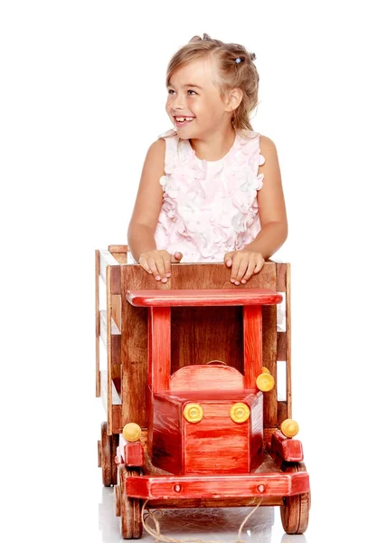 Menina está brincando com um carro de madeira . — Fotografia de Stock