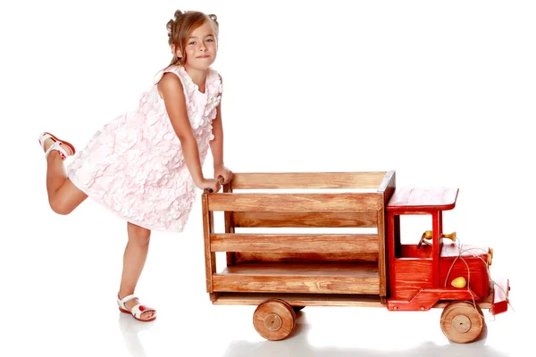 Menina está brincando com um carro de madeira . — Fotografia de Stock