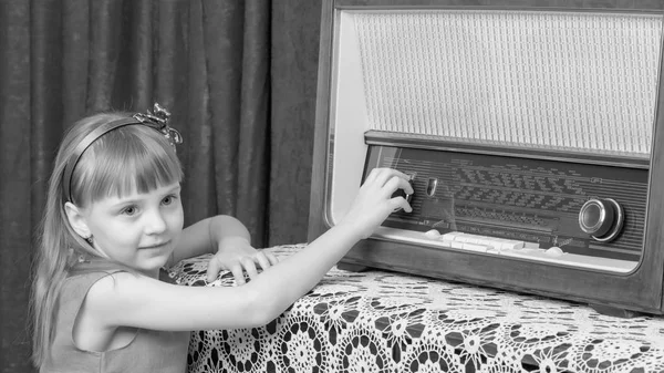 The girl turns the volume knob on the old radio. Retro style.