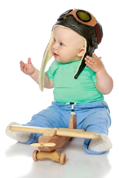 Un niño con gorra de piloto y un avión de madera en la mano — Foto de Stock