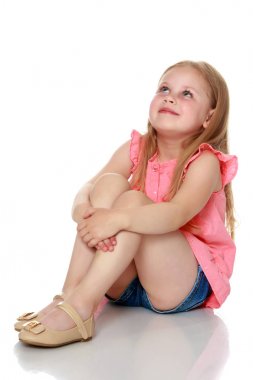 Küçük kız yerde oturuyor..