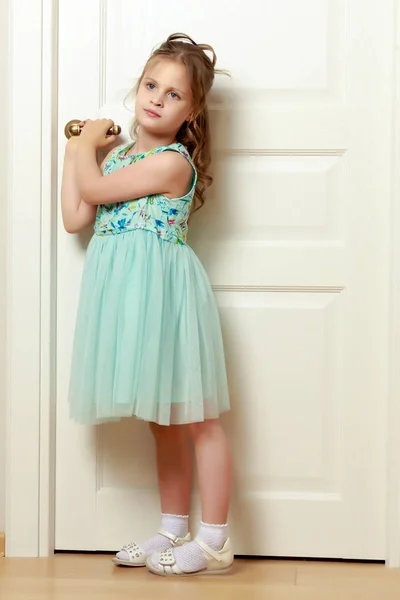 Uma menina está ao pé da porta . — Fotografia de Stock