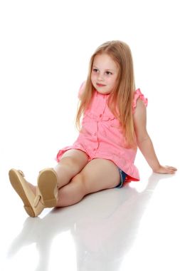 Küçük kız yerde oturuyor..