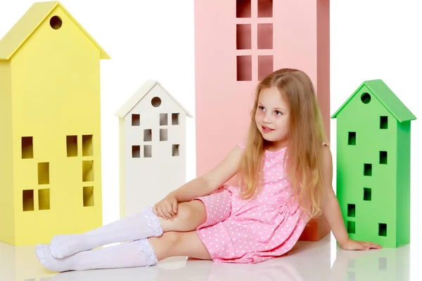 Petite fille joue avec des maisons en bois. — Photo