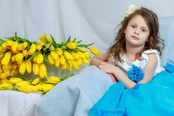 Het kleine meisje op de Bank met een boeket van bloemen. — Stockfoto