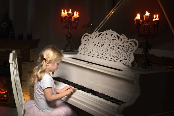 Kleines Mädchen spielt bei Kerzenschein Klavier. — Stockfoto