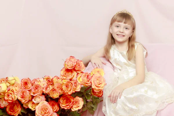 Menina senta-se ao lado de um buquê de flores . — Fotografia de Stock