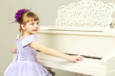 Bir kız bir Beyaz kuyruklu piyano poz.