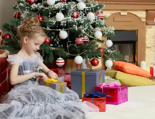 Маленькая девочка с подарком рядом с елкой . — стоковое фото