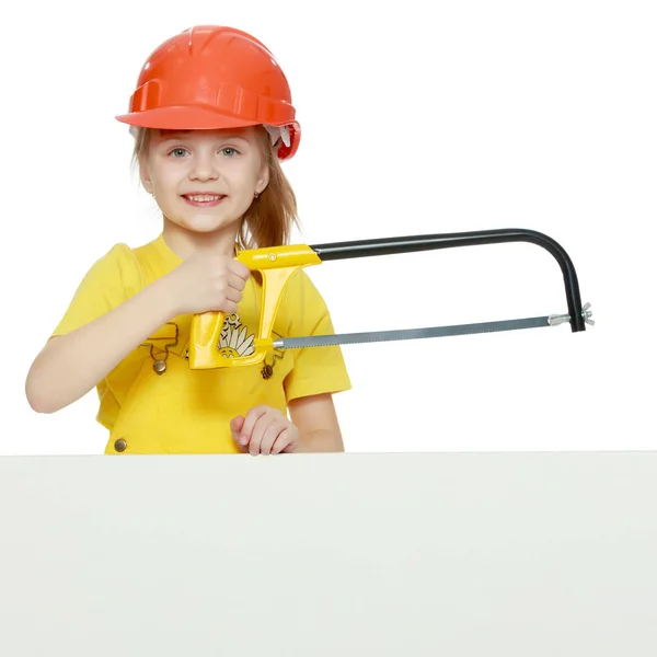 Menina em um capacete de construção espreita por trás de um outdoor . — Fotografia de Stock