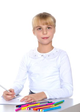 Küçük bir kız masada çizim.