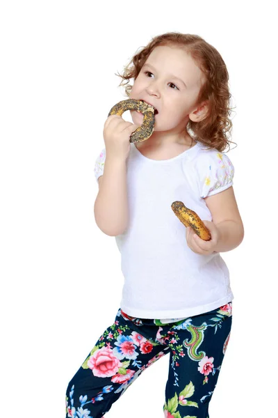 Küçük kız bir simit yemek — Stok fotoğraf