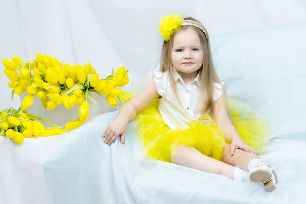 Uma menina com um buquê de tulipas amarelas . — Fotografia de Stock