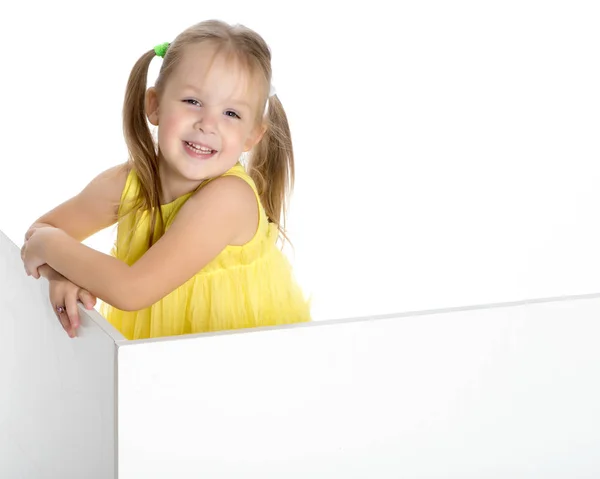 A little girl is looking from behind an empty banner. — Stock Photo, Image