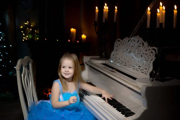 Niña toca el piano a la luz de las velas. —  Fotos de Stock