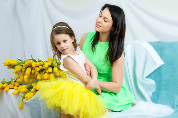 Мама и дочь на диване с букетом цветов . — стоковое фото