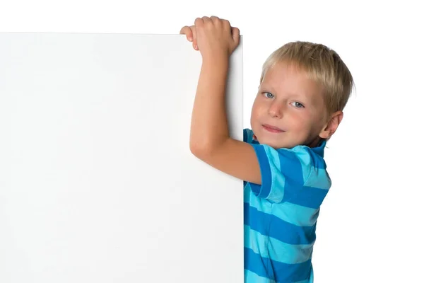 Ένα μικρό αγόρι ψάχνει από πίσω από ένα άδειο πανό. — Φωτογραφία Αρχείου