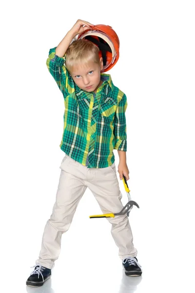 Een kleine jongen in een bouw werknemers helm houdt een inst — Stockfoto