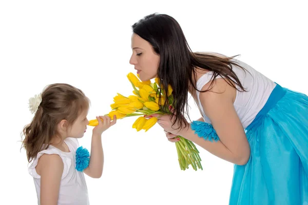 Mãe e filha cheirando tulipas amarelas . — Fotografia de Stock