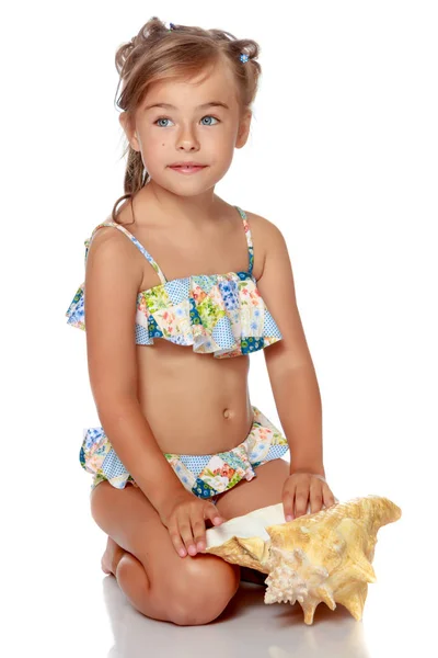 Маленькая девочка в купальнике с ракушкой — стоковое фото