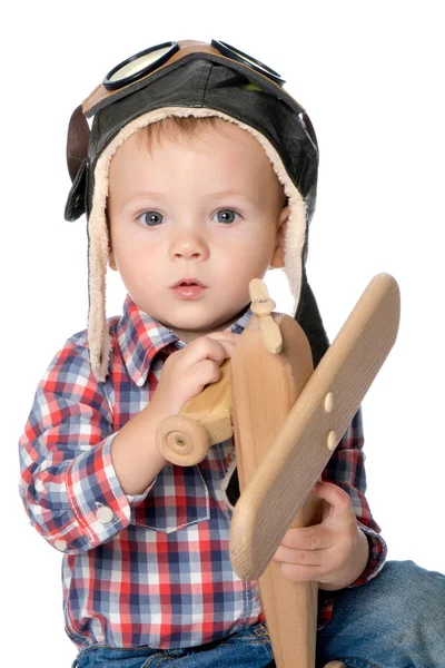 Маленький мальчик в кепке пилота и деревянный самолет в руке — стоковое фото