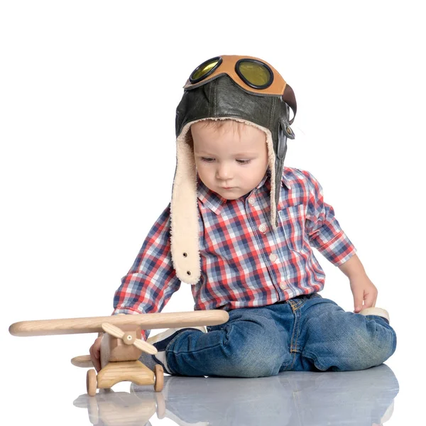 Un petit garçon avec une casquette de pilote et un avion en bois à la main — Photo