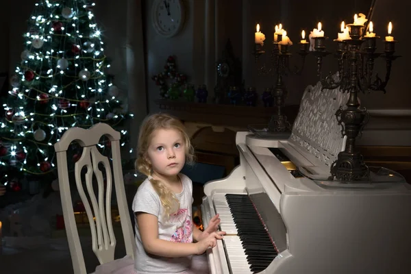 Menina toca piano à luz das velas. — Fotografia de Stock