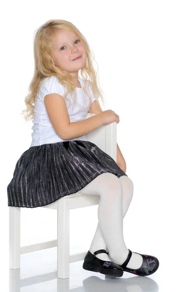A menina está sentada num banco. — Fotografia de Stock