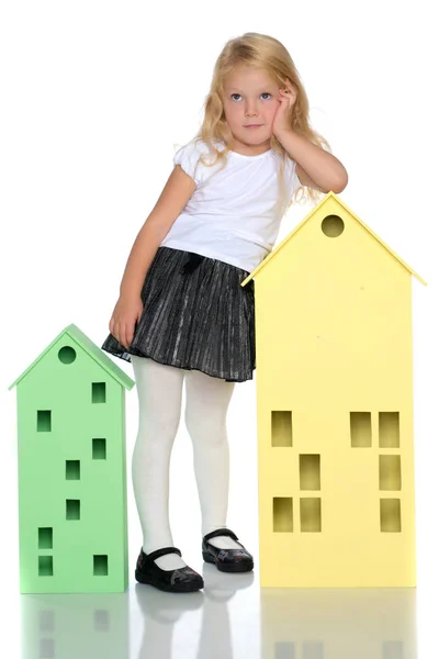 Little girl is playing with wooden houses. — Stock Photo, Image