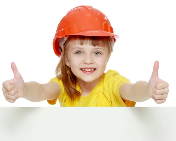 Chica en un casco de construcción asoma por detrás de una valla publicitaria . —  Fotos de Stock