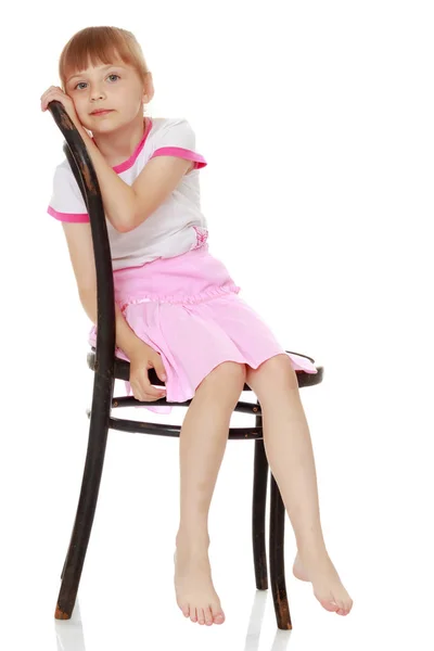 La petite fille est assise sur une chaise — Photo