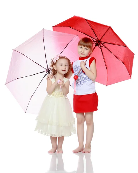 Twee meisjes staan onder paraplu 's. — Stockfoto