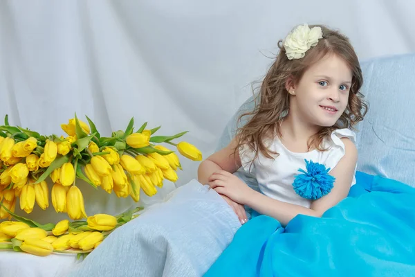 La bambina sul divano con un mazzo di fiori . — Foto Stock