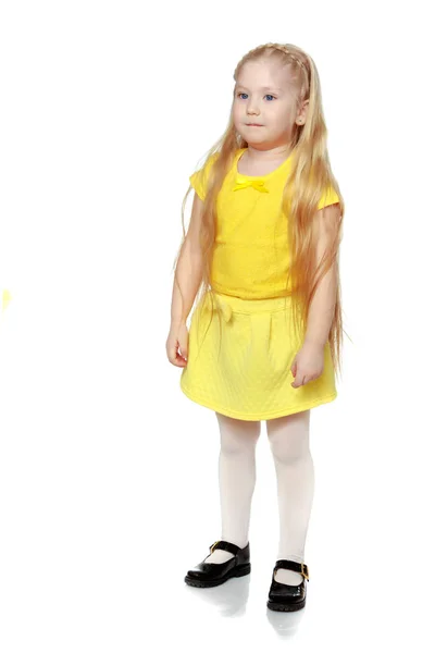 En liten blondin i en gul t-shirt. — Stockfoto