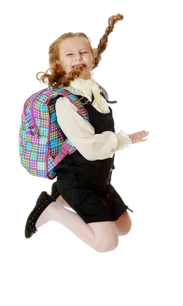 Menina estudante com uma mochila atrás dos ombros salta — Fotografia de Stock