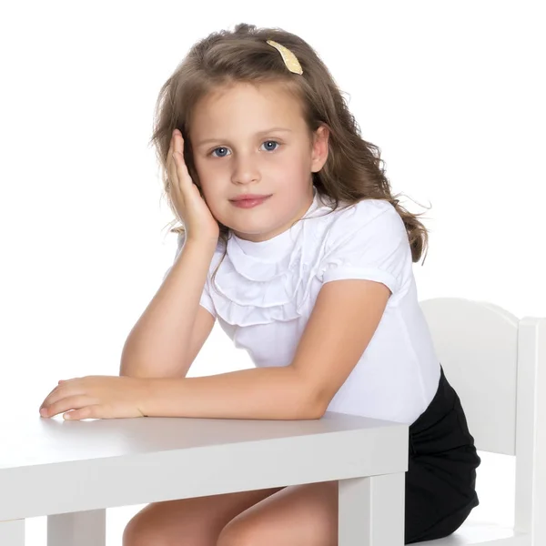 La niña está sentada en la mesa. —  Fotos de Stock