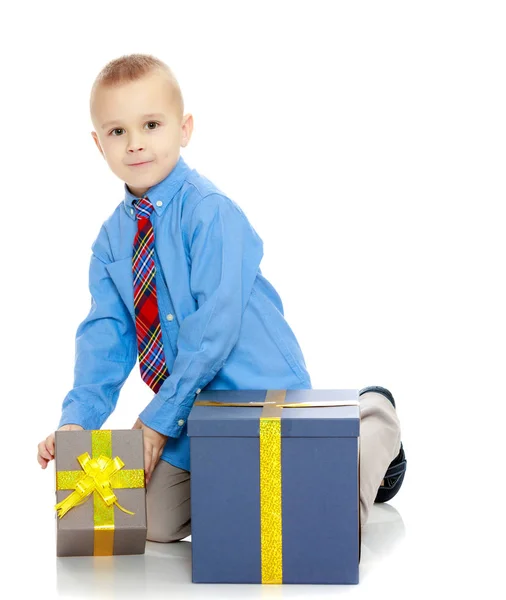 The little boy looks at the box with the gifts — Stock Photo, Image