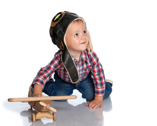 Маленький хлопчик у ковпачку пілотів і дерев'яний літак в руці — стокове фото