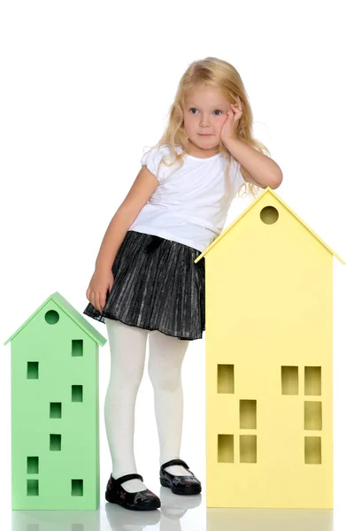 Little girl is playing with wooden houses. — Stock Photo, Image