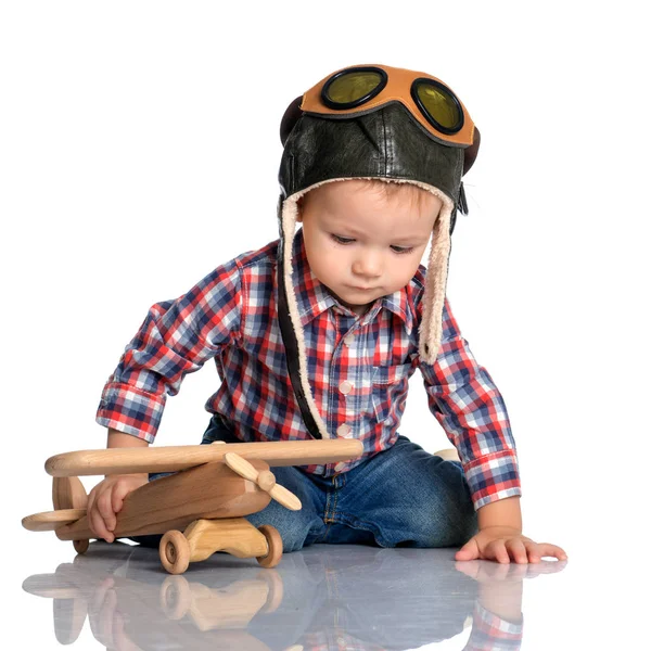 Ein kleiner Junge mit Pilotenmütze und einem Holzflugzeug in der Hand — Stockfoto