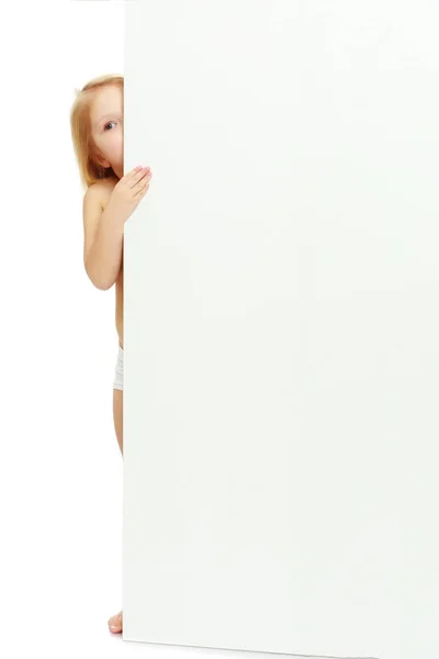 Malá holčička vykukuje ven zpoza banner. — Stock fotografie