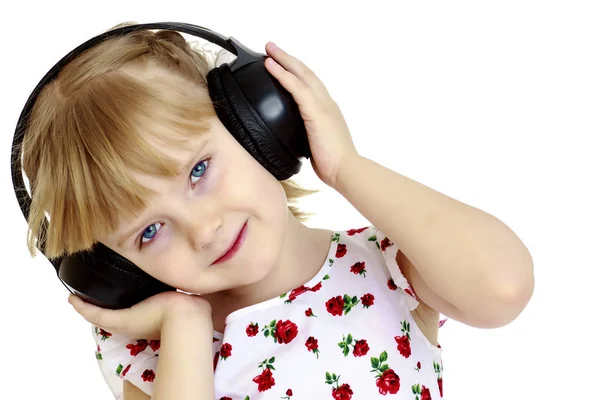 Pieni tyttö kuulokkeiden kanssa kuuntelemassa musiikkia. — kuvapankkivalokuva