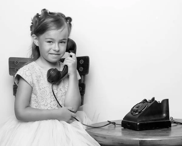 Una niña está sonando en el viejo teléfono. —  Fotos de Stock