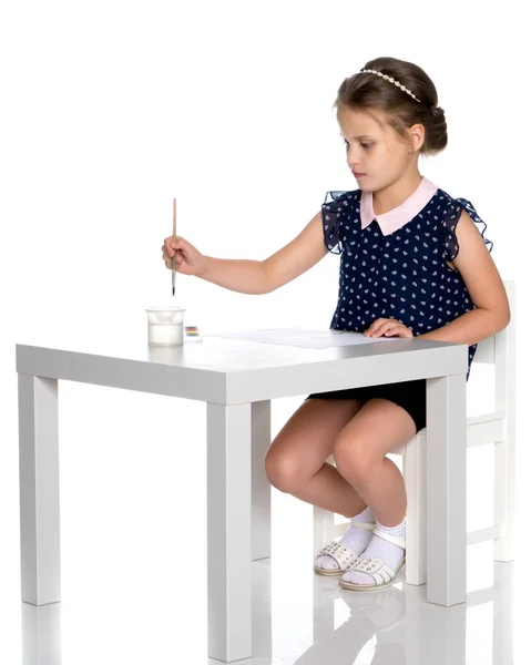 En liten flicka målar med färg och pensel. — Stockfoto