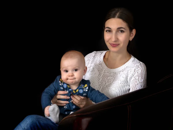 Glückliche junge Mutter mit ihrer Tochter an den Händen auf einem schwarzen Bac — Stockfoto