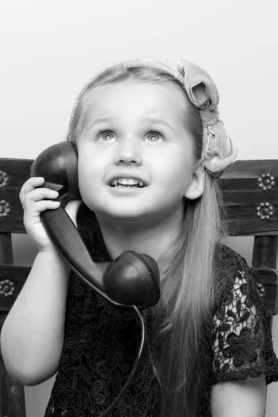 Una niña está sonando en el viejo teléfono. —  Fotos de Stock